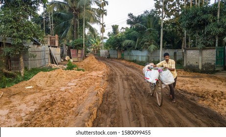 Amarpur, Tripura, India - December 2018: A Man Walks With His Cycle Loaded With Luggage On The Terrible, Muddy And Slushy Roads In Rural Tripura.