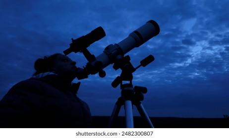 Amateur astronomer looking at the cloudy evening skies, waiting for observing planets, stars, Moon and other celestial objects with a telescope.