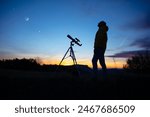 Amateur astronomer looking at the evening skies, observing planets, stars, Moon and other celestial objects with a telescope.