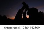 Amateur astronomer looking at the evening skies, observing planets, stars, Moon and other celestial objects with binoculars.