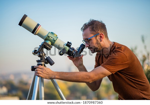 Amateur\
astronomer looking at the sky with a\
telescope.