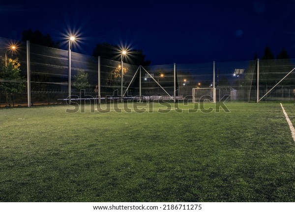 An amateur\
soccer field illuminated at night. A small football field lit by\
lanterns in the evening. Green football field illuminated at night.\
Soccer field in night with\
spotlight
