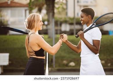 Amateur tennis players shaking hands at the net. Two sportswomen shaking hands over the net after the match. - Powered by Shutterstock