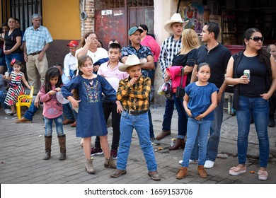 Amatitan, Jalisco, Mexico; 02 22 2020: Hispanic Extended Family With Children Stand Outside On The Street Waiting For A Charro Parade During Carnival Feast. Boys And Girls With Their Parents. 