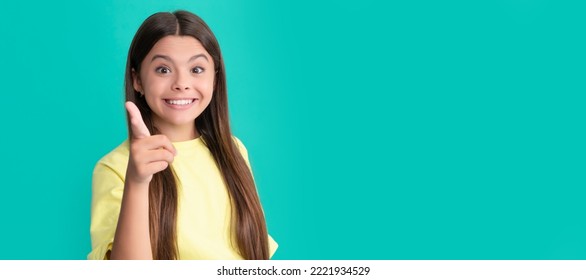 Amazed Child With Long Hair Pointing Finger On Blue Background, Advertising. Child Face, Horizontal Poster, Teenager Girl Isolated Portrait, Banner With Copy Space.