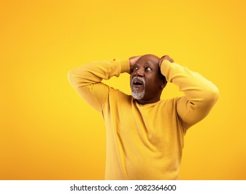 Amazed Emotional Senior Black Man Holding His Head In Shock, Looking At Copy Space For Your Text Or Advertisement, Offering Exciting Deal Over Orange Studio Background