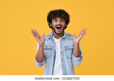 Amazed excited young indian man looking at camera with wow face expression feeling surprised advertising shopping promotion, unbelievable betting win standing isolated on yellow background. - Shutterstock ID 2118627155