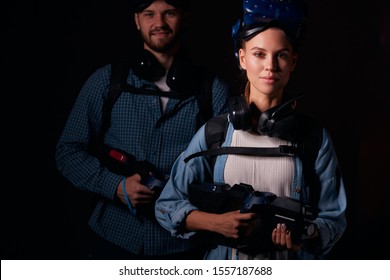 Amazed friends came to play game of virtual reality. Confident woman looking at camera isolated over black background, man stand behind woman. Hi-tech