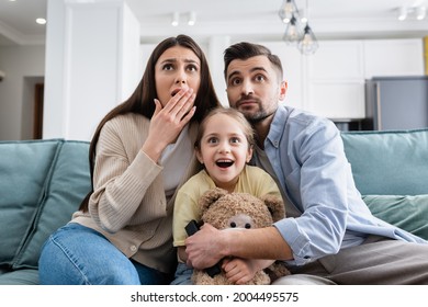 Amazed Girl Watching Movie Near Shocked Parents And Teddy Bear