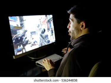 Amazed Guy Emotional Playing Computer Game Online In Dark Room