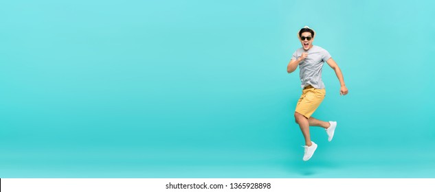 Amazed Handsome Asian Tourist Man In Summer Outfit Jumping Studio Shot Isolated On Light Blue Background