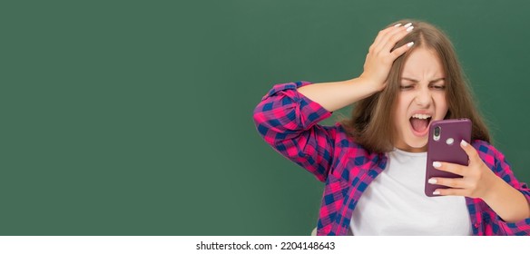 Amazed Kid Chatting On Smartphone In Classroom At Blackboard, Email Reply. Horizontal Isolated Poster Of School Girl Student. Banner Header Portrait Of Schoolgirl Copy Space.