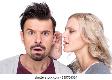 Amazed man is listening gossip in the ear from woman, on the white background.
