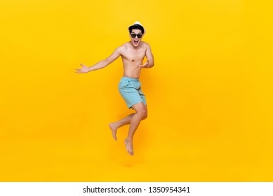 Amazed shirtless handsome Asian tourist man jumping studio shot isolated on colorful yellow background - Shutterstock ID 1350954341