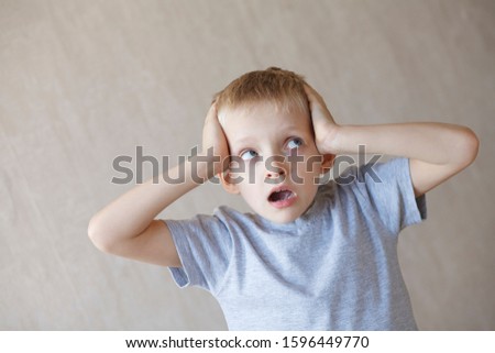 amazed or shocked little 7 years old boy holding his head with hands 