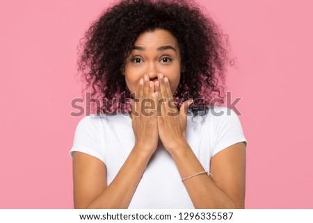 Amazed shy young african american woman covering mouth with hands looking at camera, funny black girl excited with unexpected positive surprise isolated on pink blank background studio wall, portrait