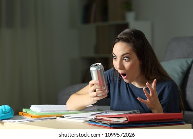 Amazed student looking at energy drink in the night at home