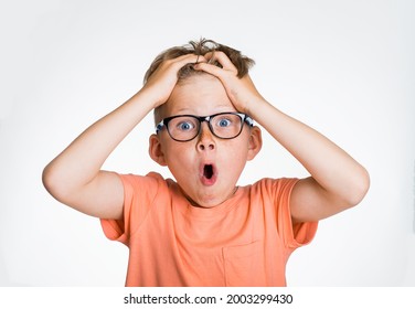 Amazed Or Surprised Child Boy With Hands On Head Isolated On White Background. Kid In Glasses With Big Eyes And Open Mouth Holding Hair On Head. Good Or Bad News