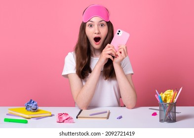 amazed surprised young blogger got million views and many likes on TikTok video, school girl sit table desk wearing pink sleep mask happy to get excellent mark on exam online education