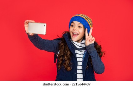 Amazed Teen Girl In Down Vest With Smartphone. Portrait Of Child Blogging With Phone.