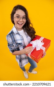 Amazed Teen Kid In Glasses With Present. Studio Shot Of Teen Kid Hold Present. Teen Kid Holding Box