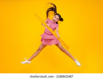 Amazed Teenager. Back To School. School Girl Hold Ruler Measuring Isolated On Yellow Background. Crazy Jump, Jumping Kids. Excited Teen Schoolgirl.