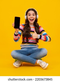 Amazed Teenager. Teenager Child Girl Holding Smartphone. Hipster Girl Types Text Message On Cell Phone, Enjoys Online Communication, Types Feedback. Kid Showing Blank Screen Mobile Phone, Mockup.