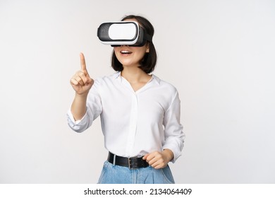 Amazed young asian woman using vr headset. Korean girl in virtual reality glasses pointing at smth and smiling, white background - Powered by Shutterstock