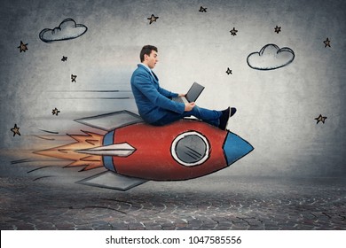 Amazed Young Businessman Flying On A Fast Rocket Looking At His Laptop Monitor. Global Network Speed Concept. Business Success And High Targets.