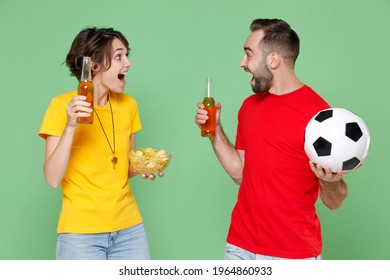 Amazed Young Couple Friends Sport Family Woman Man Football Fans In T-shirts Cheer Up Support Favorite Team With Soccer Ball Hold Beer Bottles Chips Looking At Each Other Isolated On Green Background