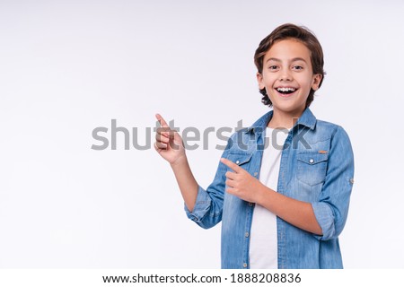 Amazed young male kid pointing at copy space isolated over white background