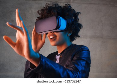 Amazed young woman touching the air during the VR experience. Horizontal studio shot.