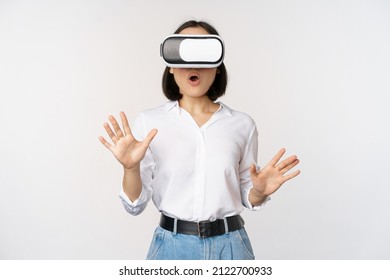 Amazed young woman in virtual reality, using vr glasses headset, standing over white background - Powered by Shutterstock