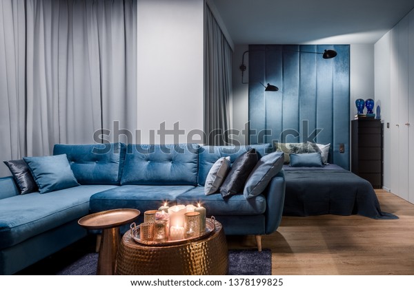 Amazing apartment in blue with corner sofa,\
copper coffee tables and open\
bedroom