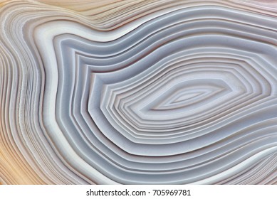 Amazing Banded Agate Crystal cross section as a background. Natural light translucent agate crystal surface, Gray abstract structure slice mineral stone macro closeup