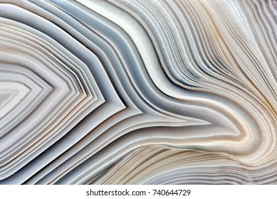 Amazing Banded Agate Crystal cross section as a background. Natural light translucent agate crystal surface, Gray abstract expressive structure slice mineral stone macro closeup
