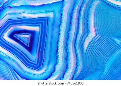 Amazing Banded Blue Agate Crystal cross section as a background. Natural light translucent agate crystal surface,  Blue abstract expressive structure slice mineral stone macro closeup