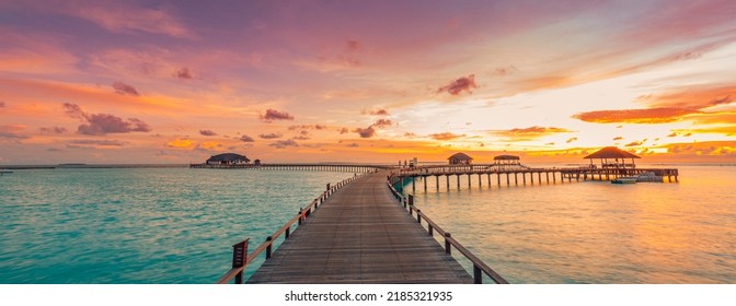 Amazing beach panoramic landscape. Beautiful Maldives sunset seascape view. Horizon colorful sea sky clouds, over water villa pier pathway. Tranquil island lagoon, vacation travel panorama background - Powered by Shutterstock