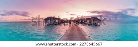 Amazing beach panoramic landscape. Beautiful Maldives sunset seascape view. Horizon colorful sea sky clouds, over water villa pier pathway. Tranquil island lagoon, vacation travel panorama background
