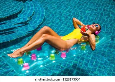 Amazing Beautiful Girl In A Yellow Bikini Air Mattress Swims In The Pool Of A Luxury Hotel, Summer Vacation, Happiness, Travel, Smile Joy, Listening To Music, Drinking Cocktail