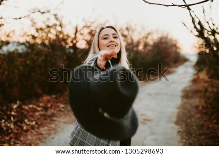 Amazing blonde woman throwing her hat forward while smiling. Beautiful european girl having fun and finishing her travel time.