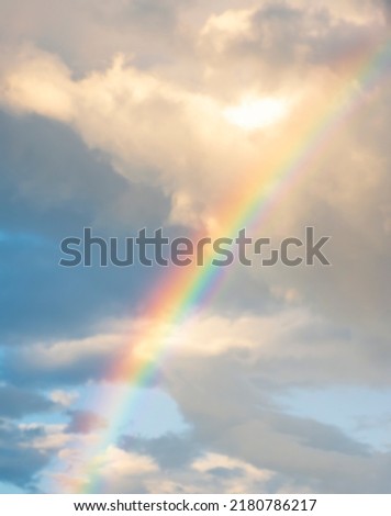 amazing bright rainbow in beautiful evening blue cloudy sky after rain and thunder with flash sun light streaming thruogh the clouds, weather thunderstorm concept
