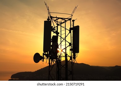 Amazing Closeup Sunset Drone View Of Silhouette Of Cell Tower. Wireless Connection. Spectacular View Of Cellular Tower With Mountains And Sea In The Background. 5G Network. Sell Site