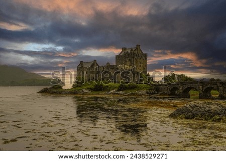 Amazing colorful clouds above Eilean Donan Castle, iconic Scottish landmark and tourist attraction. A fairytale scene with historic medieval stronghold on a small tidal island under glowing sunset sky