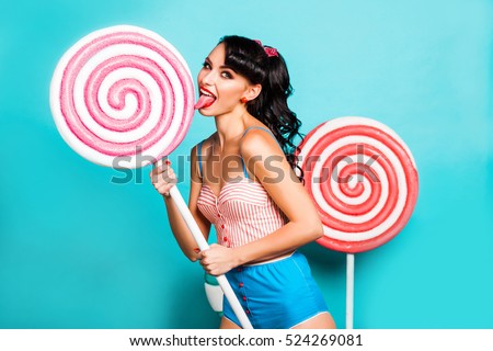 Amazing cute young pretty girl on the turquoise background holding a Huge sweets, Cake, candy, bright yellow body dresses, perfect makeup, hairstyle, fashionable Pin-up girl, cool, smiling, hollywood