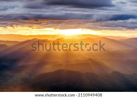 amazing dramatic cloudscape in sunset with sun rays over misty mountains landscape  