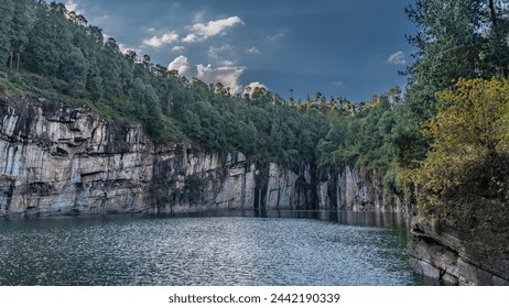 An amazing emerald lake in the crater of an extinct volcano. Steep rocky shores. A lush forest grows on the mountainside. Ripples on calm water. Clouds in the blue sky. Madagascar. Tritriva Lake - Powered by Shutterstock
