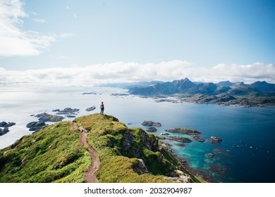 Amazing epic shot of young man hiker stand on top of mountain after long difficult hike in Lofoten Islands in Norway. Incredible summer views of scandinavian travel lifestyle. Epic landscape in north - Shutterstock ID 2032904987