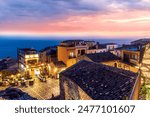 amazing evening view from mountain town to beautiful italian town with roofs and biuldings and scenic water of a sea gulf with amazing cloudy sky on background