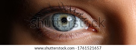 Amazing female blue and green colored wide opened eye in low light technique close-up